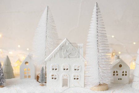 Photo for Atmospheric miniature white christmas village. Stylish little christmas houses and trees on snow blanket with glowing lights. Christmas modern winter village, holiday banner. Happy Holidays! - Royalty Free Image