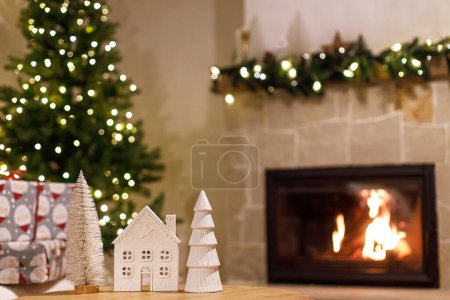 Foto de Decoración moderna de Navidad en la mesa contra la chimenea. La época de Navidad atmosférica. Elegante casa blanca y decoración del árbol en la habitación festiva, víspera de Navidad - Imagen libre de derechos