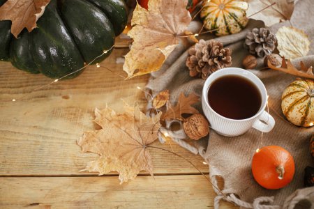 Photo for Warm cup of tea, pumpkins, fall leaves, cozy scarf on rustic wooden table with space for text. Hygge autumn banner. Happy Thanksgiving. Fall still life - Royalty Free Image