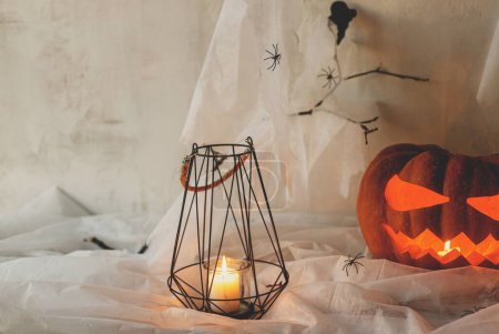 Foto de ¡Feliz Halloween! Spooky Jack o linterna calabaza tallada, telaraña, fantasma, murciélagos y velas brillantes en la noche. Espeluznantes decoraciones atmosféricas fiesta de halloween, espacio para el texto. Truco o trato - Imagen libre de derechos