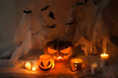 Photo for Happy Halloween! Spooky Jack o lantern carved pumpkin, spider web, ghost, bats and glowing light in dark. Scary atmospheric halloween party decorations, space for text. Trick or treat - Royalty Free Image