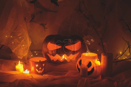 Foto de ¡Feliz Halloween! Spooky Jack o linterna calabaza tallada, telaraña, fantasma, murciélagos y luz brillante en la oscuridad. Espeluznantes decoraciones atmosféricas fiesta de halloween, espacio para el texto. Truco o trato - Imagen libre de derechos