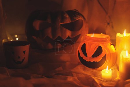 Foto de ¡Feliz Halloween! Spooky Jack o linterna calabaza tallada, tela de araña, cubo de caramelo, arañas y luz brillante en la oscuridad. Decoraciones de fiesta de Halloween atmosféricas de miedo. Truco o trato - Imagen libre de derechos