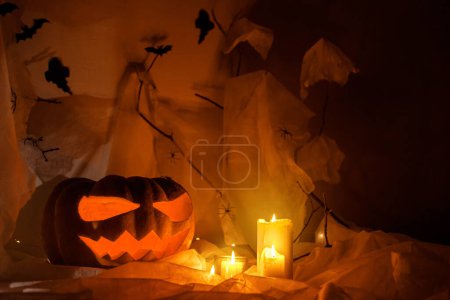 Foto de Spooky Jack o linterna calabaza tallada, telaraña, fantasma, murciélagos y luz brillante en la oscuridad. ¡Feliz Halloween! Espeluznantes decoraciones atmosféricas fiesta de halloween, espacio para el texto. Truco o trato - Imagen libre de derechos