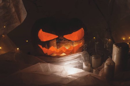 Foto de ¡Feliz Halloween! Spooky Jack o linterna calabaza tallada, telaraña, fantasma y luz brillante en la oscuridad. Espeluznantes decoraciones atmosféricas fiesta de halloween, espacio para el texto. Truco o trato - Imagen libre de derechos