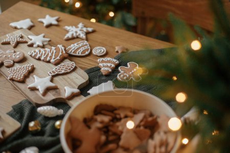 Photo for Merry Christmas! Gingerbread cookies with icing on wooden table with fir branches and festive decorations on background of christmas tree golden lights. Atmospheric Christmas eve, family holidays - Royalty Free Image