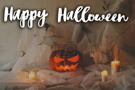 Téléchargez les photos : Joyeux Halloween ! Joyeux texte d'Halloween et effrayante lanterne Jack o citrouille sculptée avec toile d'araignée et bougies incandescentes en soirée. Carte de voeux halloween atmosphérique effrayante, panneau manuscrit - en image libre de droit