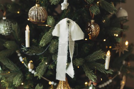 Téléchargez les photos : Élégant arbre de Noël décoré avec des boules vintage, des rubans, des bougies et des lumières dorées. Vacances d'hiver dans l'atmosphère. branches d'arbre de Noël avec des ornements modernes gros plan - en image libre de droit
