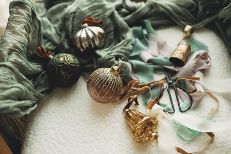 Photo for Stylish christmas vintage baubles, ribbons, brass bells and scissors on cozy white chair. Christmas ornaments aesthetics flat lay. Decorating for christmas holidays. Merry Christmas - Royalty Free Image