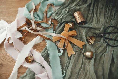 Photo for Wrapping christmas gift. Stylish festive ribbons, bow, scissors, bells and modern decorations on wooden table, top view. Merry Christmas and Happy holidays! - Royalty Free Image