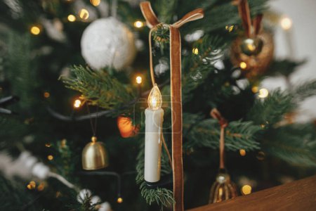 Foto de ¡Feliz Navidad! Vela de Navidad con estilo en el árbol de cerca. Hermoso árbol de Navidad decorado con adornos vintage, cintas y luces. Fondo de Navidad. - Imagen libre de derechos