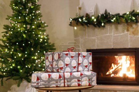 Téléchargez les photos : Joyeux Noël ! Cadeaux de Noël enveloppés élégants, arbre de Noël avec des lumières festives et cheminée à combustion confortable. Veille de Noël atmosphérique, temps des fêtes. - en image libre de droit