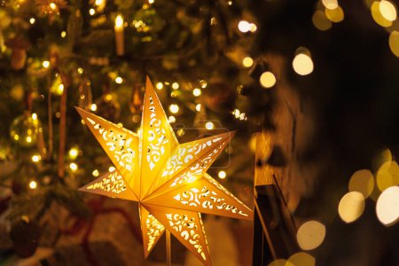 Foto de Nochebuena atmosférica. Elegante estrella iluminada de Navidad, árbol de Navidad con luces doradas y chimenea decorada festiva en la habitación escandinava noche. Feliz Navidad.! - Imagen libre de derechos