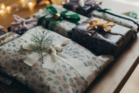 Foto de ¡Feliz Navidad! Elegantes regalos de Navidad, papel de regalo festivo, cintas, adornos vintage, campanas de latón en la mesa de madera. Preparación de las vacaciones de invierno atmosféricas - Imagen libre de derechos