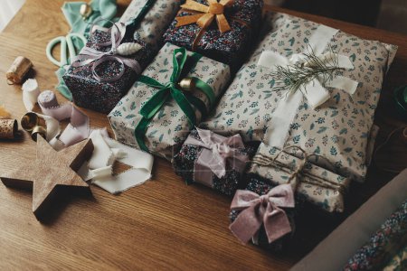 Téléchargez les photos : Cadeaux de Noël élégants, papier d'emballage festif, rubans, ornements vintage, cloches en laiton sur table en bois. Joyeux Noël ! Préparation aux vacances d'hiver atmosphériques - en image libre de droit