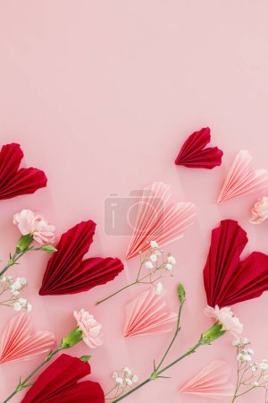 Téléchargez les photos : Joyeuse Saint Valentin ! Coeurs roses et rouges élégants avec des fleurs plates posées sur fond rose avec de l'espace pour le texte. Valentines coeurs découpes de papier. Concept de fête de l'amour et des mères - en image libre de droit