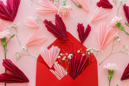 Foto de ¡Feliz San Valentín! Elegantes corazones de color rosa y rojo, flores y sobre rojo plano yacen sobre fondo rosa. Valentines corazones recortes de papel. Concepto de amor y día de la madre - Imagen libre de derechos