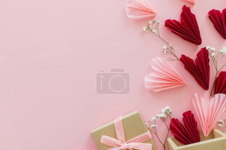 Téléchargez les photos : Joyeuse Saint Valentin ! Coeurs roses et rouges élégants, fleurs et coffret cadeau à plat reposent sur fond rose, espace pour le texte. Valentines coeurs découpes de papier et boîte artisanale. Amour et fête des mères - en image libre de droit