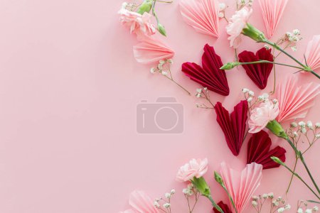 Téléchargez les photos : Joyeuse Saint Valentin ! Coeurs roses et rouges élégants avec des fleurs plates posées sur fond rose avec de l'espace pour le texte. Valentines coeurs découpes de papier. Concept de fête de l'amour et des mères - en image libre de droit