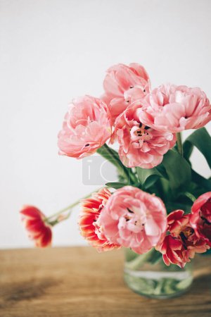 Foto de Hermosos tulipanes en jarrón sobre fondo rústico. Elegante ramo floral. Feliz día de San Valentín y feliz día de la madre. Flores rosadas y rojas tiernas - Imagen libre de derechos