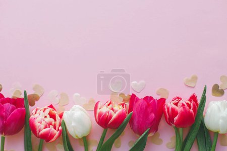 Téléchargez les photos : Coeurs élégants et tulipes sur fond rose à plat. Joyeuse Saint Valentin et joyeuse fête des mères. Découpes de papier de coeur d'or de frontière de Valentine. Modèle de bannière, espace pour le texte - en image libre de droit