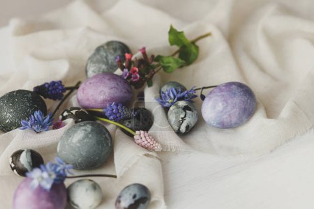 Photo for Stylish easter eggs, gentle spring flowers and linen cloth on rustic white table. Space for text. Happy Easter! Natural painted marble and purple eggs. Seasons greetings - Royalty Free Image