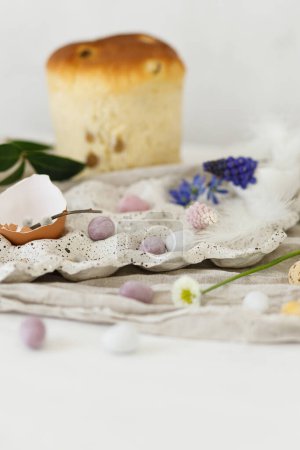 Photo for Colorful easter chocolate eggs, easter bread, spring flowers and linen cloth on rustic wooden table. Easter modern simple decoration and homemade traditional cake. Happy Easter! - Royalty Free Image