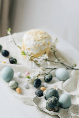 Photo for Stylish easter eggs, panettone and spring flowers on linen cloth on rustic table. Natural dye eggs and cherry blossom, festive minimal still life. Happy Easter! - Royalty Free Image