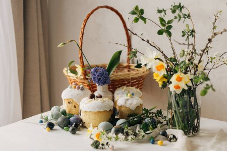 Photo for Happy Easter! Stylish easter eggs, easter bread, basket and spring flowers on linen napkin on rustic table. Natural painted marble eggs, daffodils bouquet and holiday food - Royalty Free Image