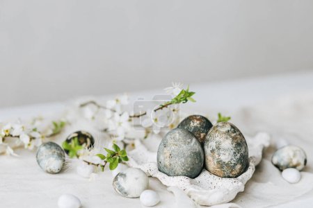 Téléchargez les photos : Joyeux Pâques ! Des œufs de Pâques élégants et des fleurs de printemps sur une table rustique en lin. Oeufs en marbre peint naturel en plateau et fleurs de cerisier. Nature morte minimale moderne - en image libre de droit