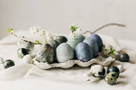 Photo for Happy Easter! Stylish easter eggs and spring flowers on linen rustic table. Natural painted marble blue eggs in tray and cherry blooms. Modern minimal still life - Royalty Free Image