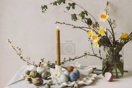 Téléchargez les photos : Joyeux Pâques ! Des œufs de Pâques élégants dans un plateau, une fleur de cerisier et une bougie sur une table rustique. Oeufs en marbre teint naturel moderne et fleurs de printemps. Pâques nature morte dans la maison de campagne - en image libre de droit
