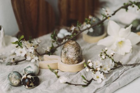 Photo for Stylish easter eggs, bunnies and cherry blossom composition on rustic table. Happy Easter! Modern natural dyed marble eggs and spring flowers. Rural still life - Royalty Free Image