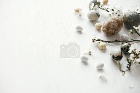 Photo for Stylish easter eggs and cherry blossom on rustic white table. Happy Easter! Minimal easter border template with space for text. Modern natural dye marble eggs and spring flowers - Royalty Free Image