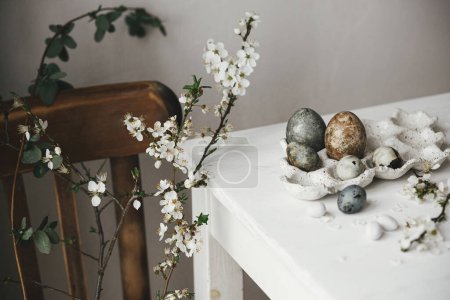 Photo for Happy Easter! Stylish easter eggs in tray and cherry blossom on rustic table. Modern natural dye marble eggs and spring flowers still life. Rural easter composition - Royalty Free Image