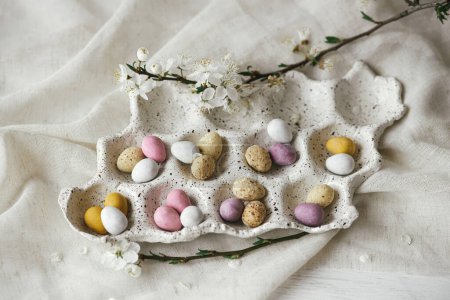 Photo for Happy Easter! Stylish colorful easter eggs in tray and cherry blossom on rustic table with linen cloth flat lay. Natural candy chocolate eggs with spring flowers. Easter hunt - Royalty Free Image
