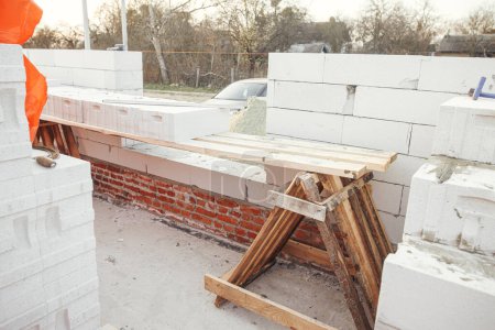 Masonry. Laying autoclaved aerated concrete blocks with reinforcement and adhesive. Installing white blocks close up.  Process of house building at construction site