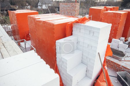 Téléchargez les photos : Autoclaved aerated blocks on concrete foundation, process of house building. Stacks of white aerated blocks for laying on concrete foundation. Building materials at construction site - en image libre de droit