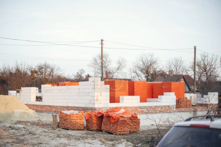 Photo for Autoclaved aerated blocks on concrete foundation and bricks, process of house building. Building materials at construction site. Stacks of white aerated blocks for laying. - Royalty Free Image