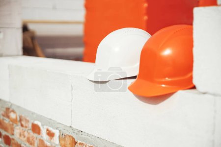 Foto de Hard hats on autoclaved aerated concrete blocks at construction site. Architecture and development. Safety helmets on white blocks. House building concept - Imagen libre de derechos