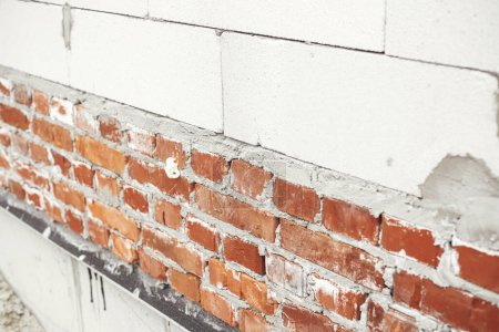 Foto de Albañilería autoclavada bloques de hormigón aireado y ladrillos sobre cimientos de hormigón. Colocando paredes con bloques blancos. Proceso de construcción de viviendas en obra - Imagen libre de derechos