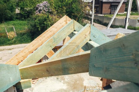 Photo for Unfinished roof trusses, view in attic with rafters and beams against sky. Wooden roof framing. Mansard of modern farmhouse building construction. - Royalty Free Image