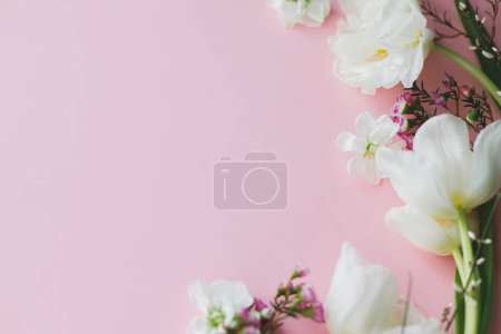 Foto de Feliz Día de las Madres. Flores elegantes planas yacen sobre fondo rosa con espacio para el texto. Tulipanes tiernos blancos y borde de flores de primavera, plantilla de tarjeta de felicitación. Banner floral. Feliz día de las mujeres - Imagen libre de derechos