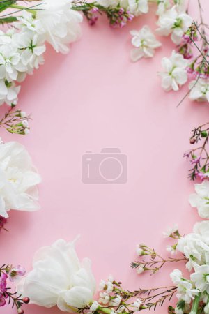 Téléchargez les photos : Joyeuse fête des mères et de la femme. Élégantes fleurs blanches à plat posé sur fond rose, espace pour le texte. Belles tulipes tendres et cadre de fleurs de printemps, modèle de carte de vœux. Bannière florale - en image libre de droit