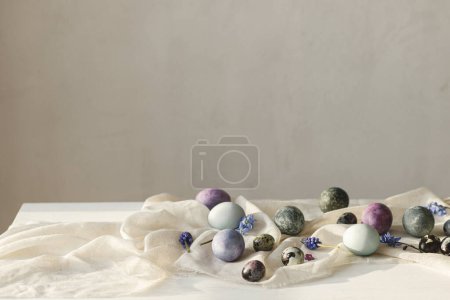 Photo for Happy Easter! Stylish easter eggs and spring flowers on linen cloth on rustic white table. Easter modern simple banner, space for text. Natural painted marble and purple eggs still life - Royalty Free Image