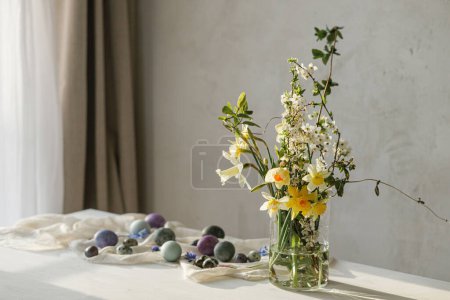 Photo for Happy Easter! Stylish easter eggs and spring flowers bouquet on rustic wooden table in rural room. Easter modern simple decor, natural painted marble eggs. Season's greetings - Royalty Free Image