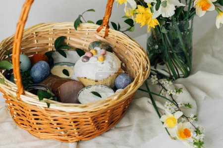 Photo for Happy Easter! Stylish easter basket with natural dyed eggs, meat, bread, butter, beets and spring flowers on rustic table. Traditional easter orthodox holiday food and daffodils bouquet - Royalty Free Image
