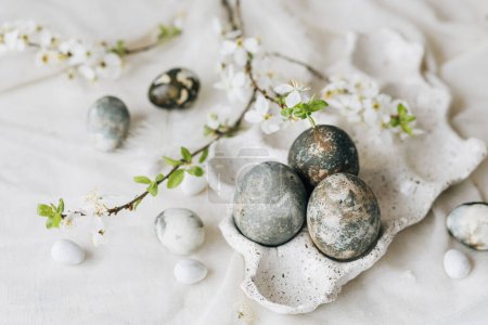 Photo for Stylish Easter eggs and spring flowers on rustic table. Happy Easter! Natural dye marble eggs in tray and cherry blossoms. Happy Easter! Holiday minimal still life - Royalty Free Image