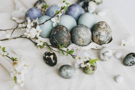 Photo for Happy Easter! Stylish easter eggs and spring flowers on linen rustic table. Natural painted marble eggs in tray and cherry blooms. Modern minimal still life - Royalty Free Image