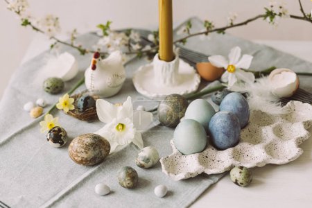 Téléchargez les photos : Joyeux Pâques ! Des œufs de Pâques élégants dans un plateau, une fleur de cerisier et une bougie sur une table rustique. Oeufs en marbre teint naturel moderne et fleurs de printemps. Pâques nature morte dans la maison de campagne - en image libre de droit